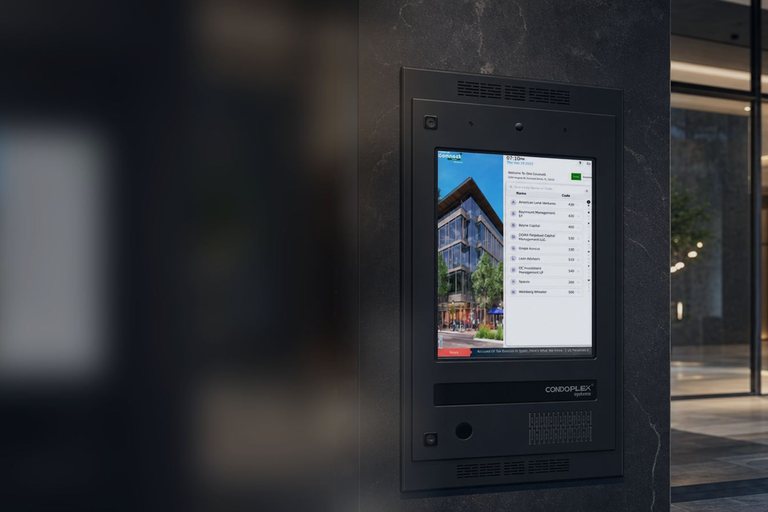 Condoplex touchscreen entry phone mounted on a stone pillar at a building entrance at night